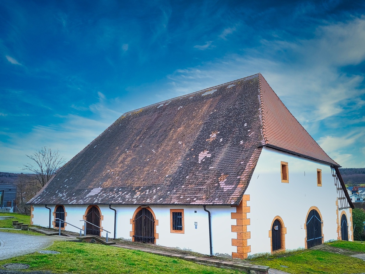 Historische Kelter in Birkenfeld-Gräfenhausen – Immobilienbewertung durch Schwebius Immobilien Großes historisches Fachwerkgebäude mit steilem, teilweise abgenutztem Ziegeldach und weißen Wänden in ländlicher Umgebung
