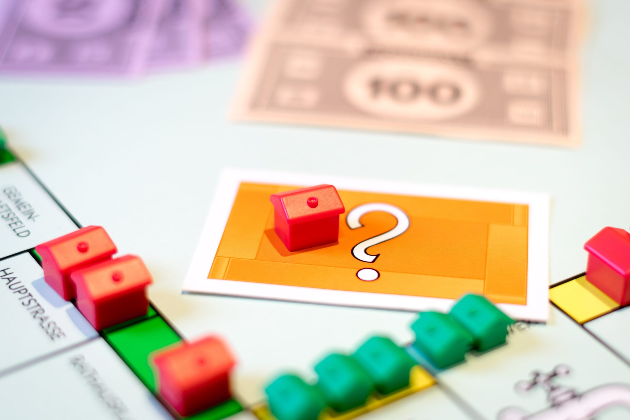 Spielbrett mit kleinen roten Häusern und einem Fragezeichen auf einer Karte